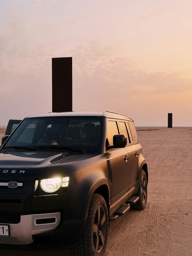 Black 4x4 vehicle parked in the desert under a blush dusk sky
