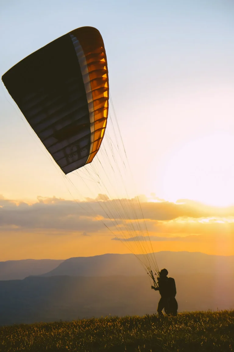 Paraglider launching from a hilltop at golden hour