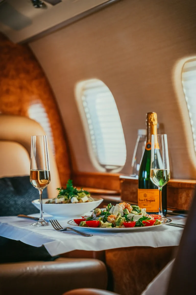 Private jet cabin with a table set with champagne and food