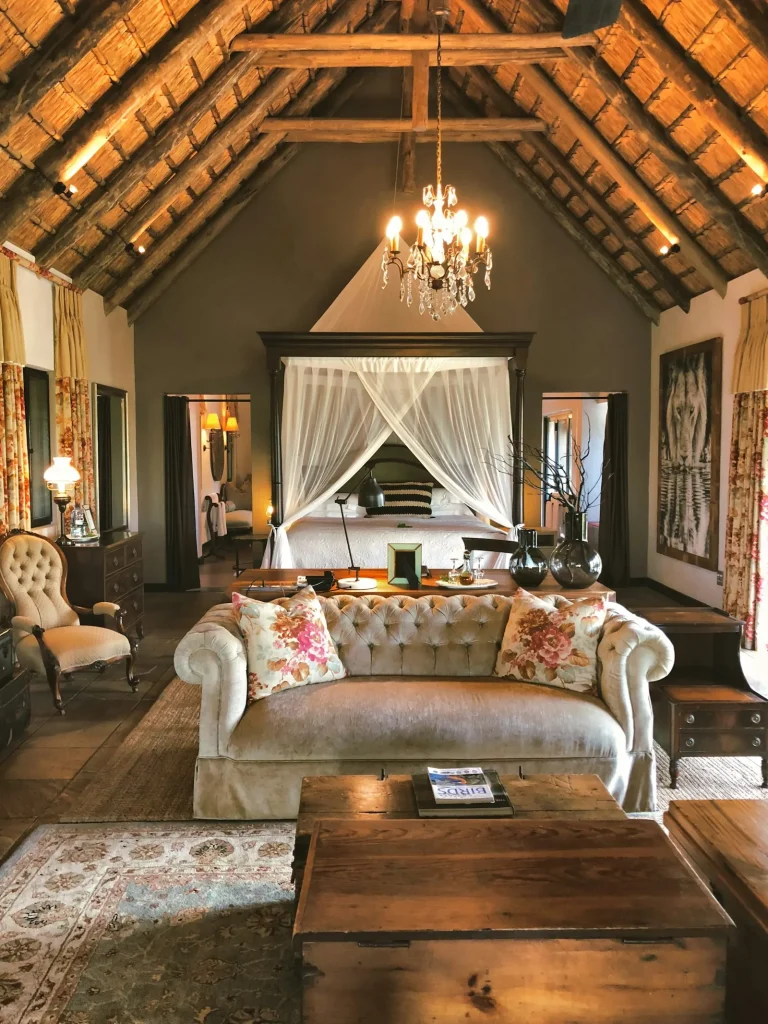 Thatched lodge suite with a chandelier, canopy bed and vintage sofa