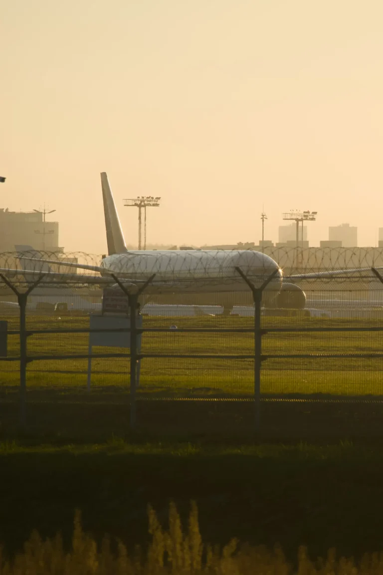 Aeroplane on the airport apron behind a perimeter fence in golden evening haze
