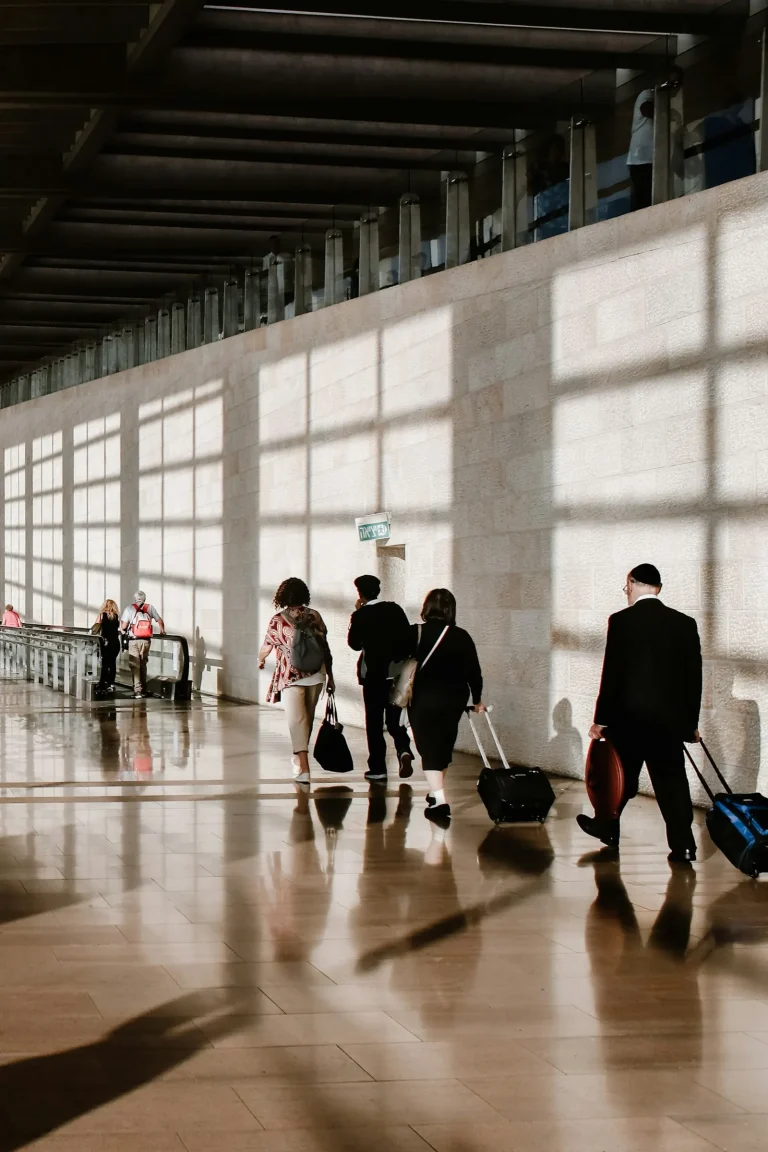 Travellers with luggage walking through a sunlit airport terminal