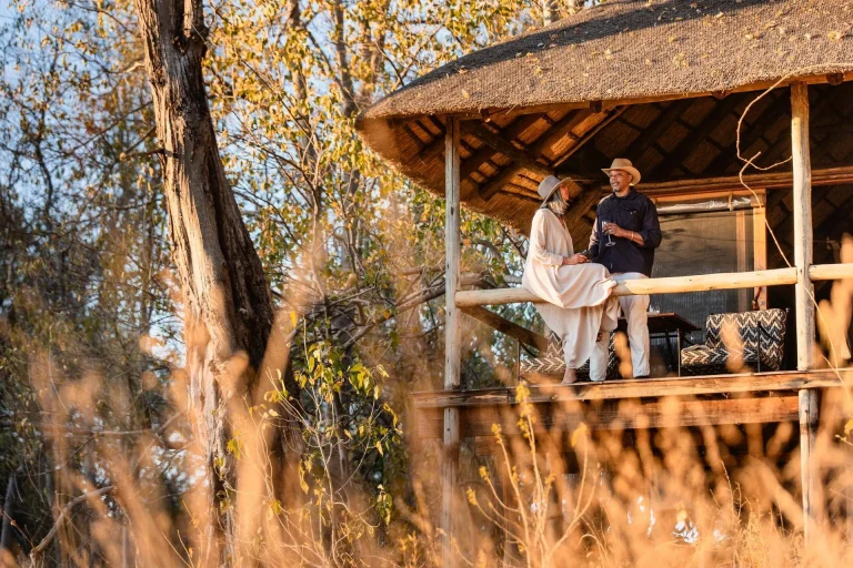 Guests on a raised tent deck at sunset in Botswana