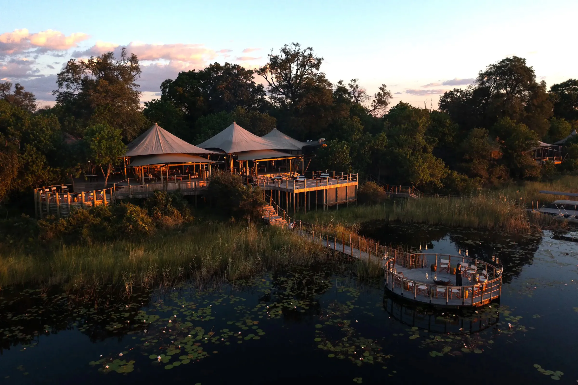 Tented camp reflected in a lagoon at dusk