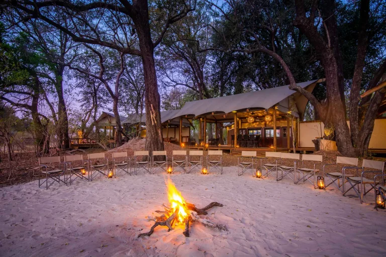 Kwara camp lit by lanterns and a campfire at dusk