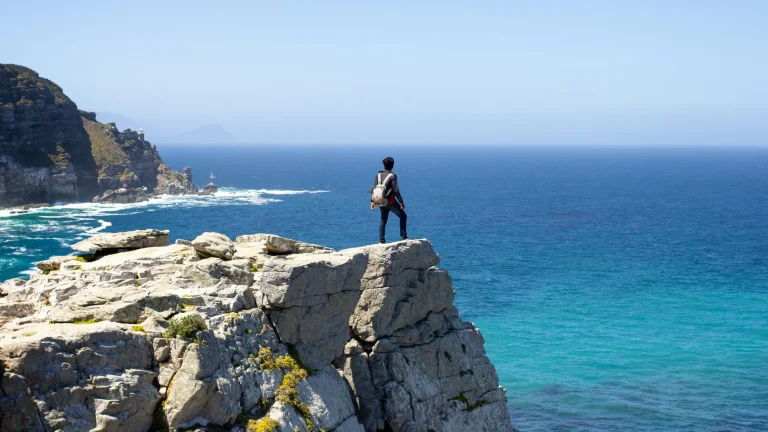 Hiker on the rocks above turquoise water on the Peninsula