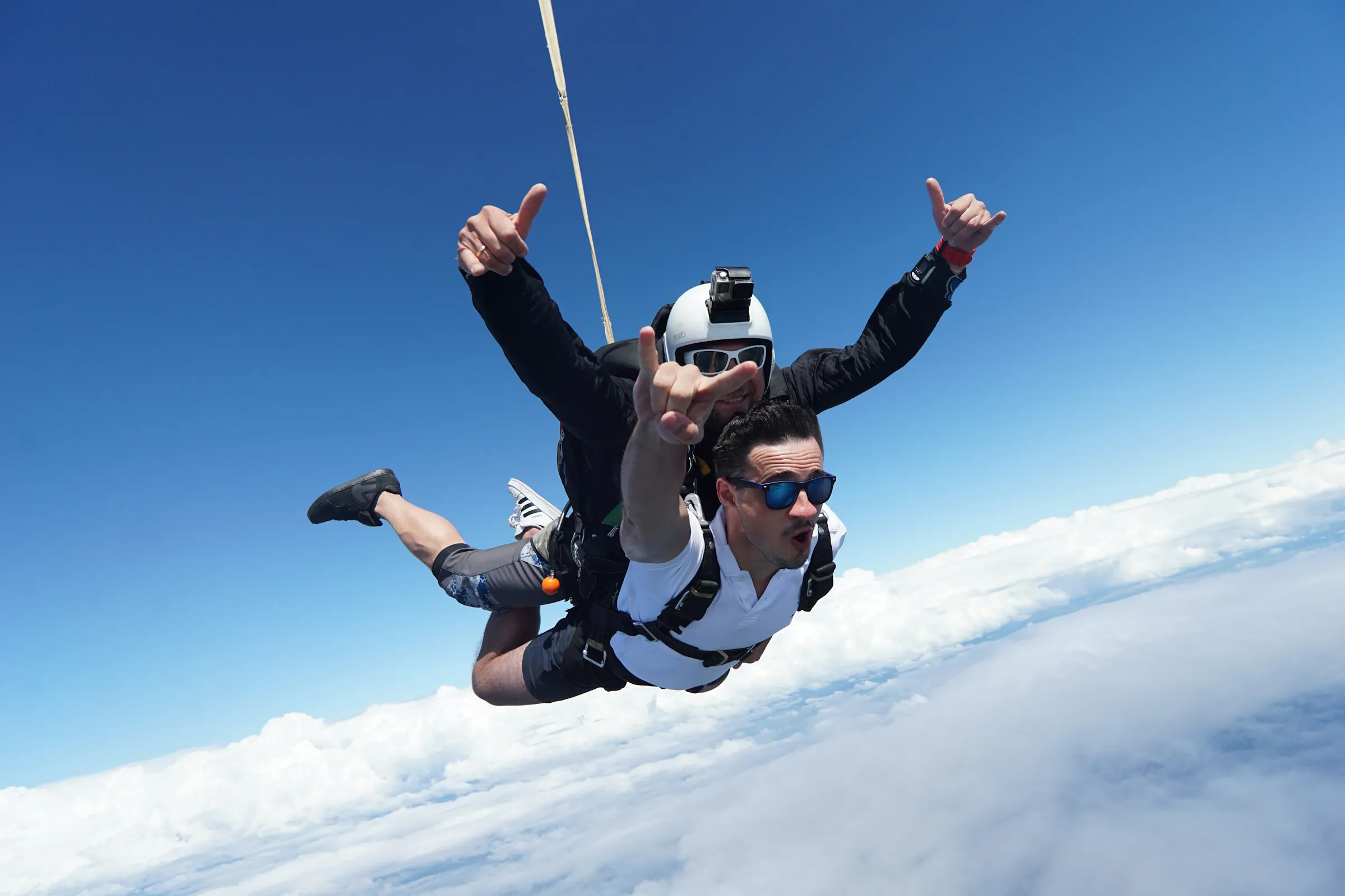 Tandem skydivers in freefall above the clouds