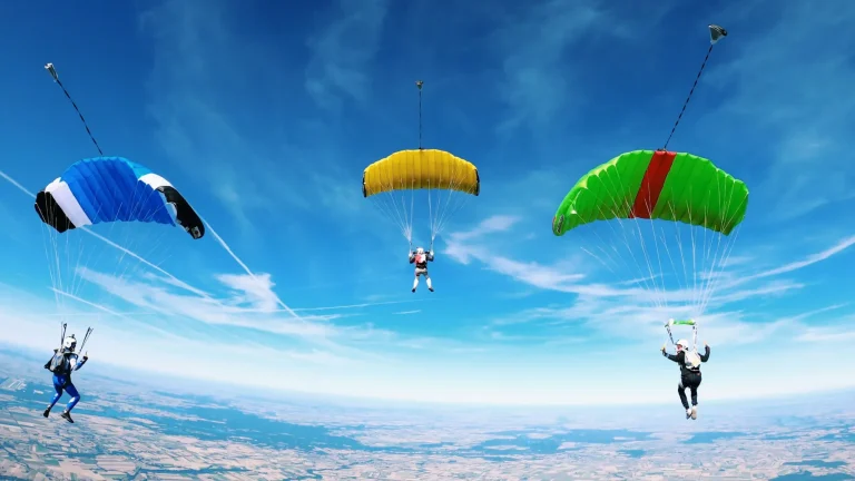 Parachutes open against a blue sky