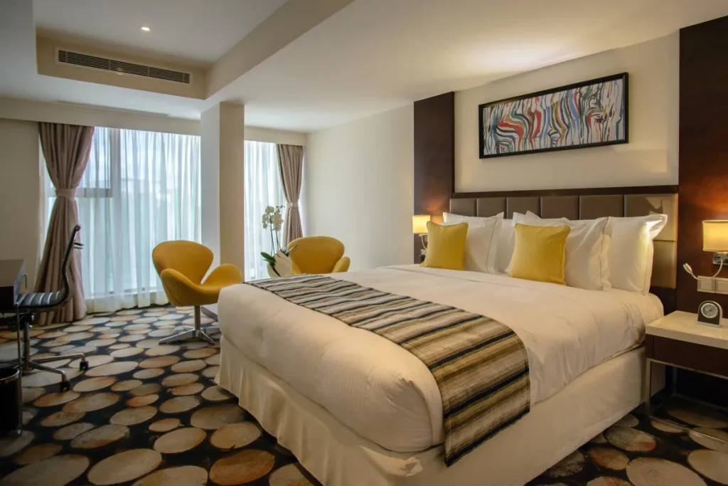 King room with a striped throw and city-view windows at The Concord Hotel