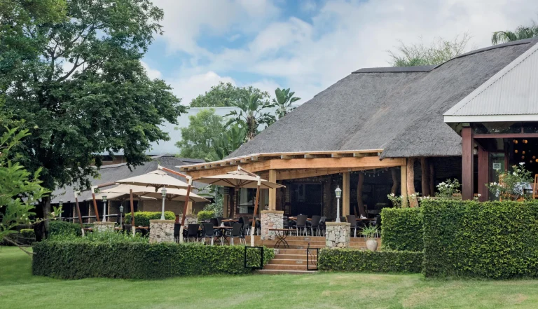 Thatched main building and gardens at Hippo Hollow Country Estate