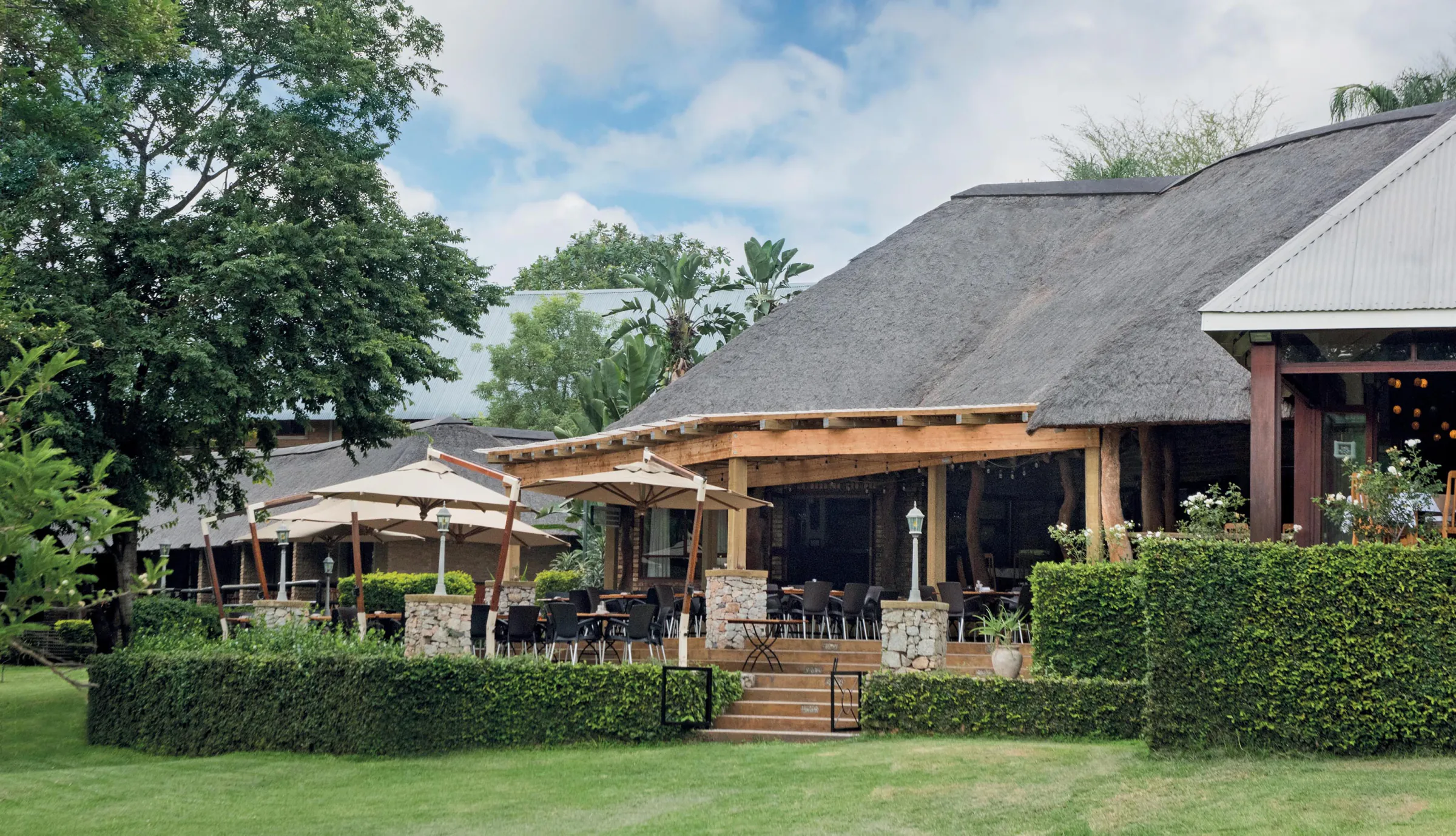 Thatched main building and gardens at Hippo Hollow Country Estate