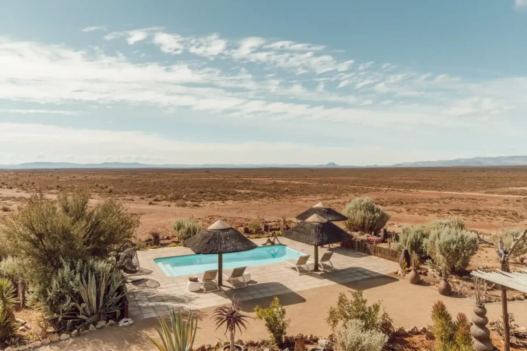 Pool and thatched umbrellas overlooking the Karoo plains at Inverdoorn