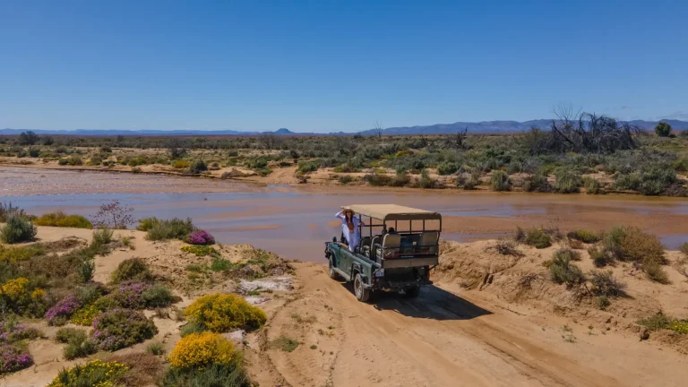 Game drive vehicle beside the river at Inverdoorn