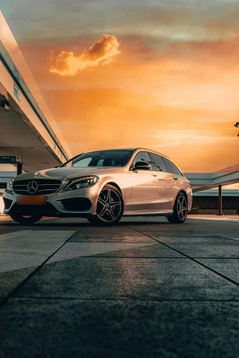 Silver Mercedes-Benz estate under a canopy against an orange sunset sky