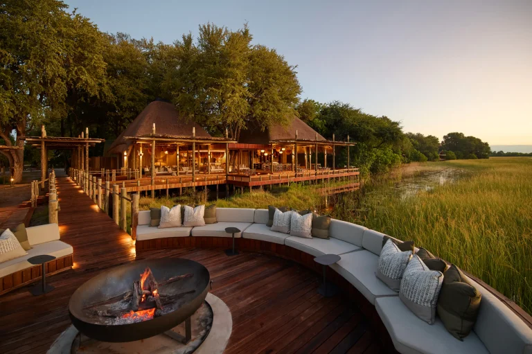 Lodge deck and fire pit over the Okavango floodplain at dusk