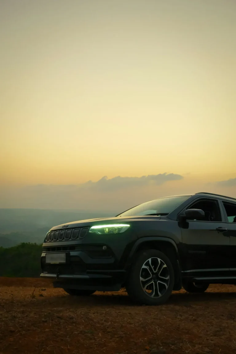 Black SUV parked on a hilltop at sunset