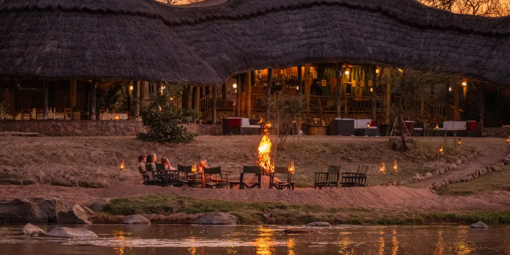 Ruaha River Lodge lit up at dusk beside the river