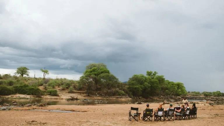 Chairs set out on the dry riverbed in Ruaha under a stormy sky