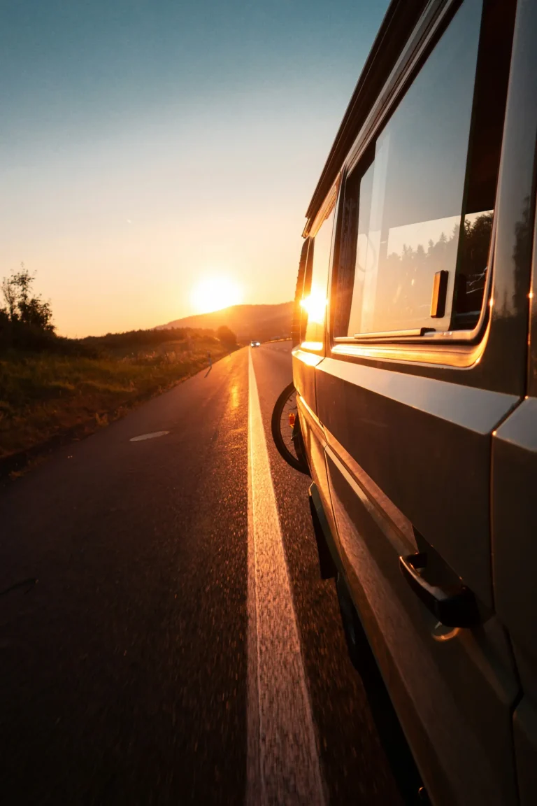 Van parked beside an empty road with the sun setting behind the hills